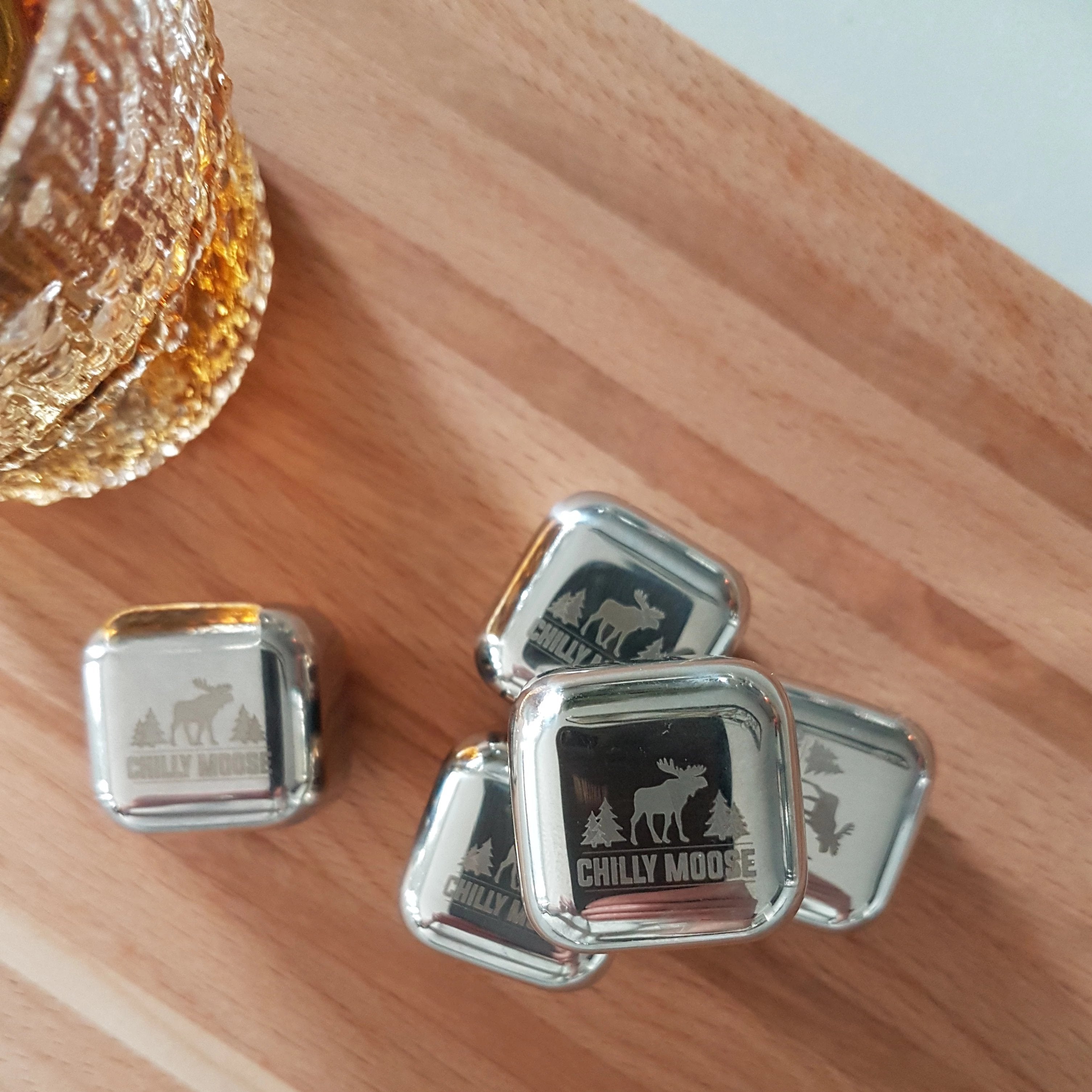 Stack of 5 Chilly Moose stainless steel Chilly Ice Cubes on a wooden cutting board